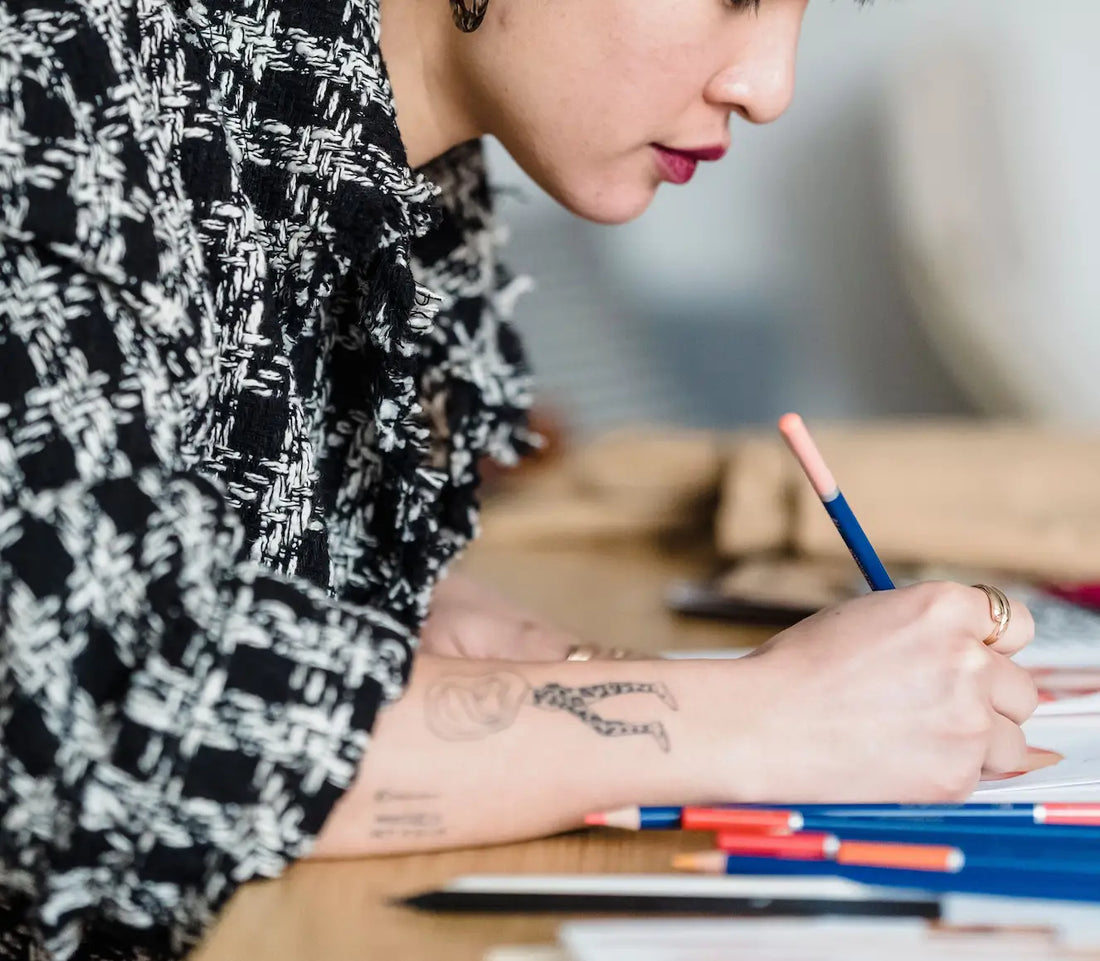 Personne dessinant avec des crayons de couleur sur un carnet